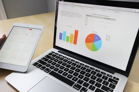 A laptop and tablet show web stats in the form of lists, a bar graph, and a pie graph