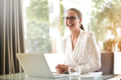 A woman sitting in front of a laptop, smiling