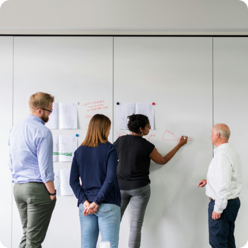 people collaborating and writing on a whiteboard