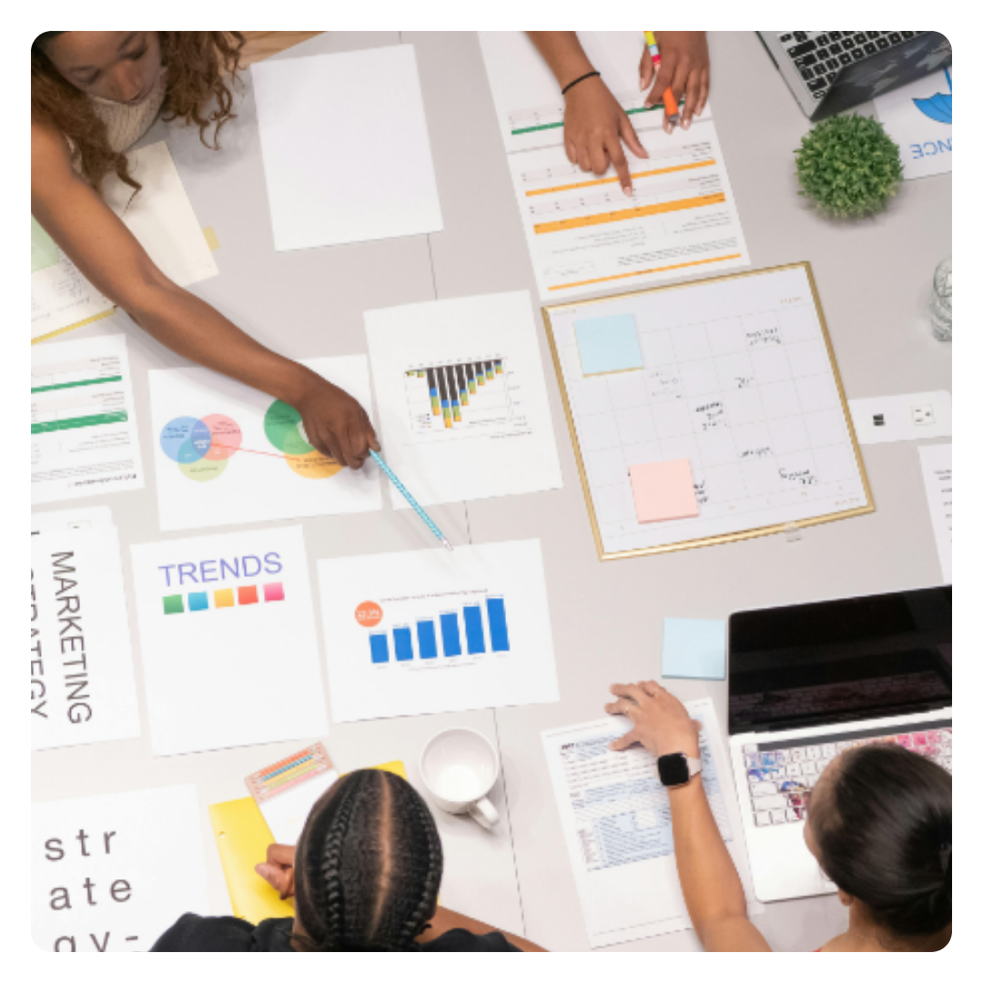 a group of people collaborating with a laptop and paper reports laid out on a table