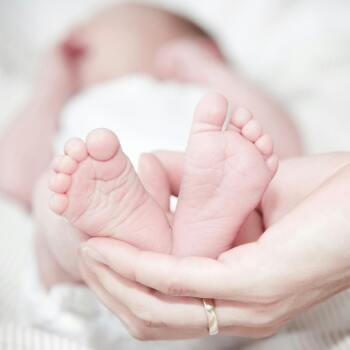 a hand holding a baby's feet